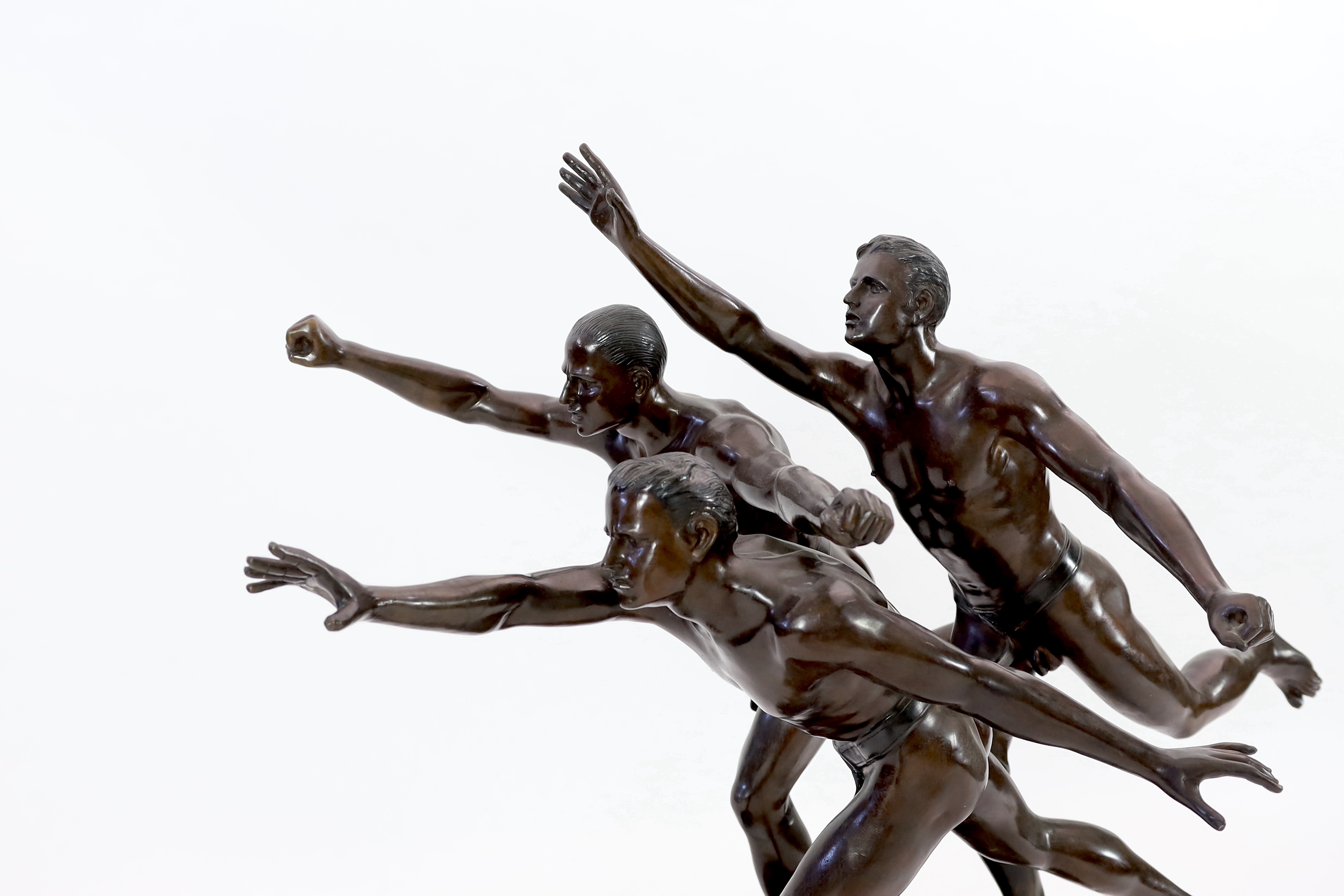 After Alfred Boucher (French, 1850-1934). A large bronze group of three runners at the finishing line, 'Au But', 128cm long, 78cm deep, 111cm high